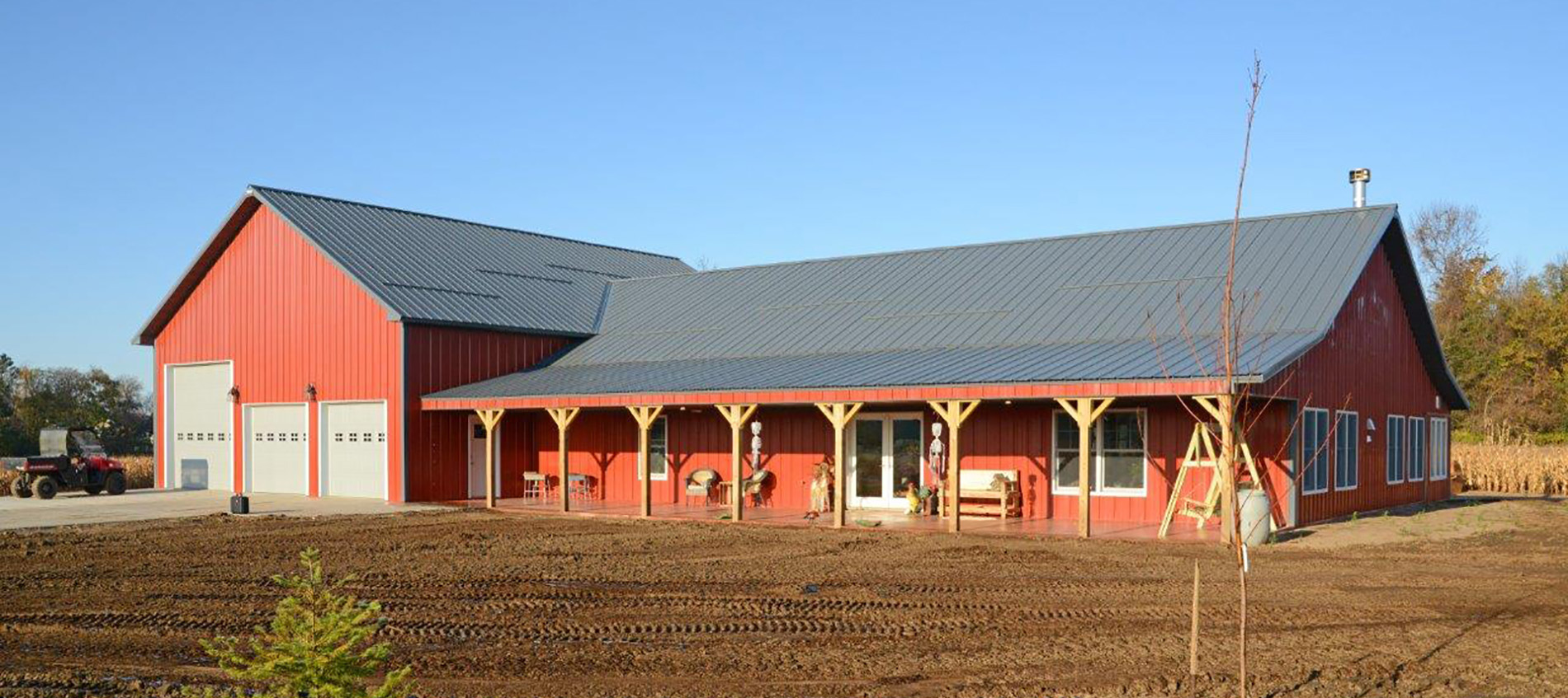 StewBer Buildings featured project: Red and white residential shouse located in Pepin, Wisconsin with three garage doors and extended front porch and awning